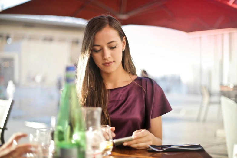 a woman sitting at a table using a cell phone, perfect readability, square, drink, avatar image