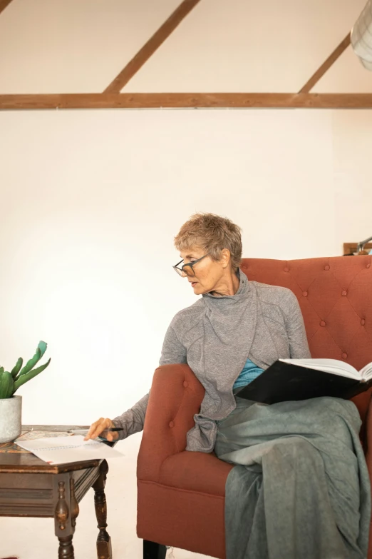 a woman sitting in a chair reading a book, sol retreat, profile image, high-quality photo, casually dressed