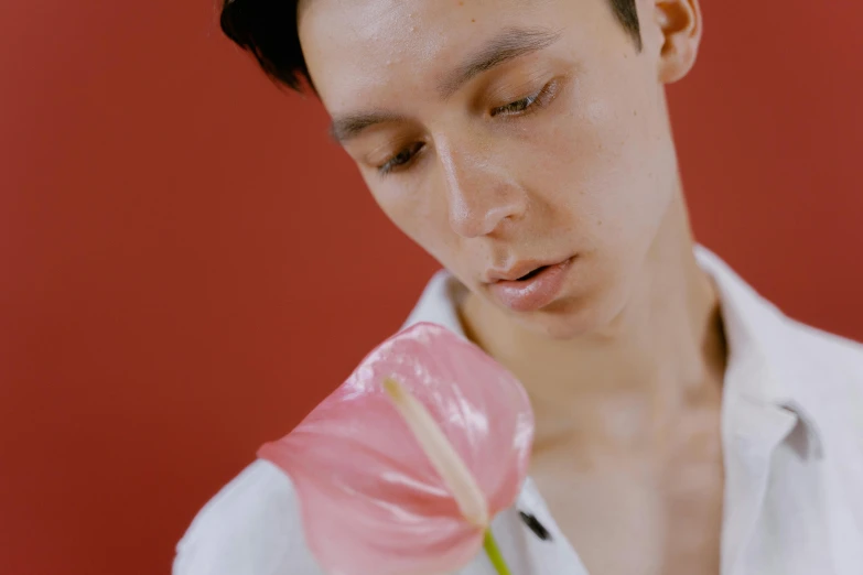 a man in a white shirt holding a pink flower, inspired by Russell Dongjun Lu, trending on pexels, hyperrealism, kiko mizuhara, red irises and a slim face, non binary model, holding a red orchid