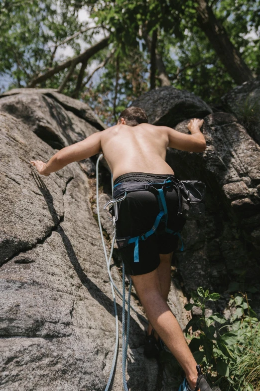 a man climbing up the side of a rock, unsplash, figuration libre, wearing a tank top and shorts, showing her shoulder from back, harnesses and garters, boys