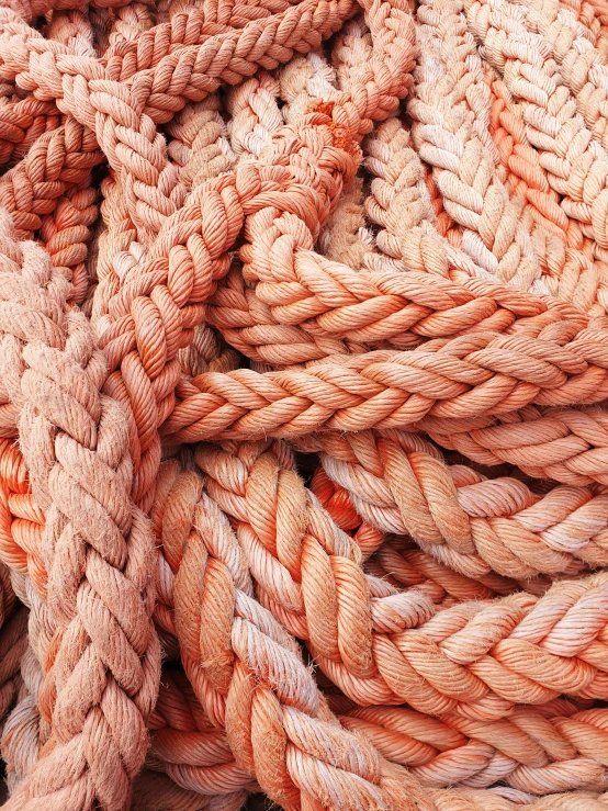 a pile of orange rope sitting on top of a table, by Jessie Algie, unsplash, light pink tonalities, set sail, reds, grain”