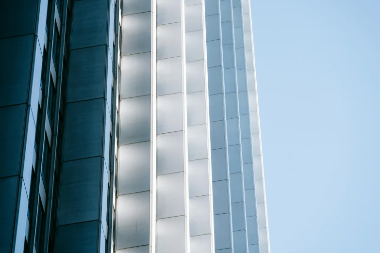 a couple of tall buildings next to each other, inspired by Zaha Hadid, unsplash, light and space, metal panels, blue and silver, square lines