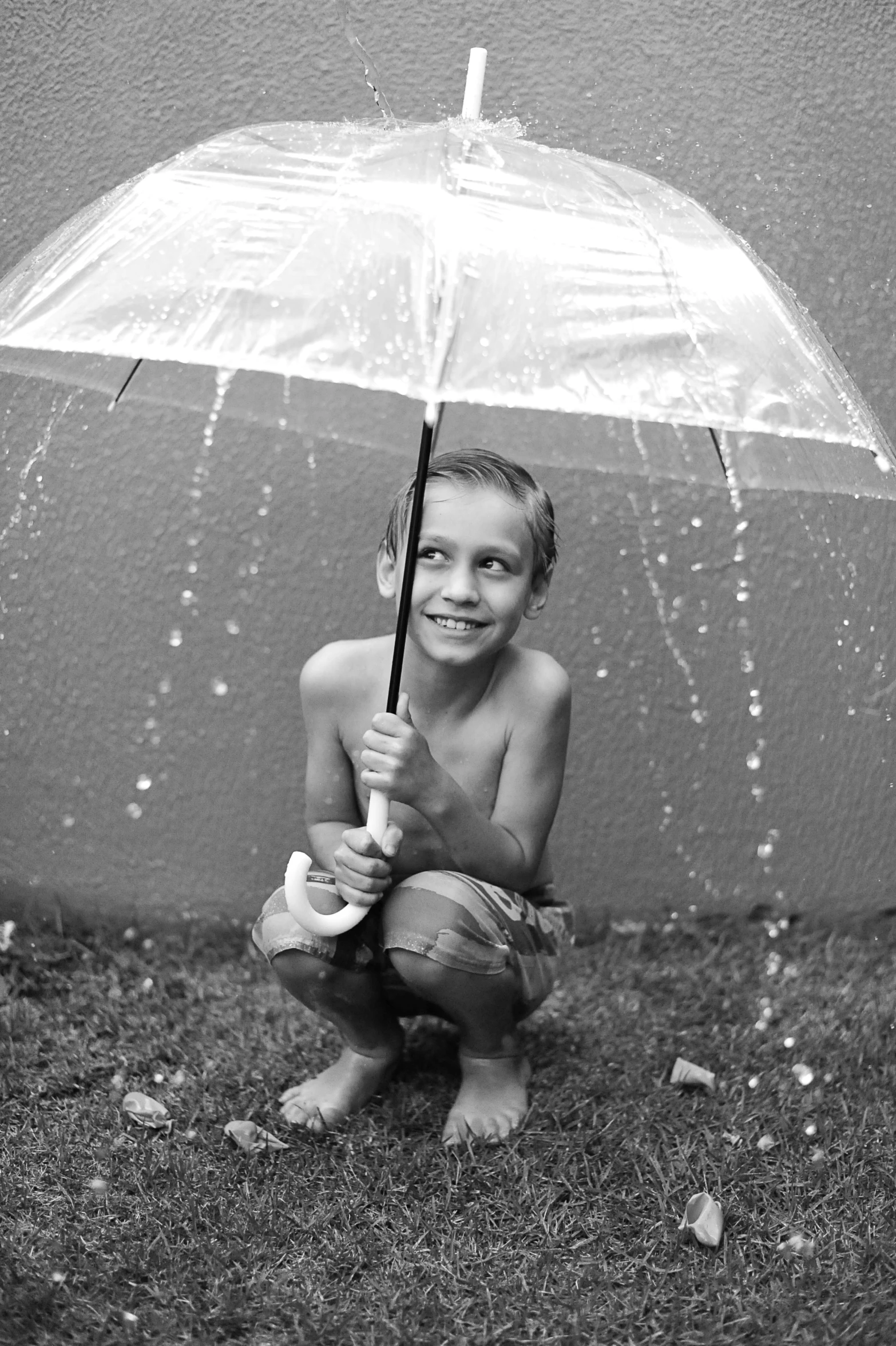 a black and white photo of a young boy holding an umbrella, pexels contest winner, dripping with water, a still of a happy, 256435456k film, ( ( photograph ) )