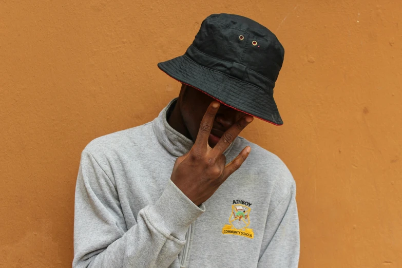 a man talking on a cell phone while wearing a hat, an album cover, unsplash, realism, bucket hat, main colour - black, academic clothing, federation clothing