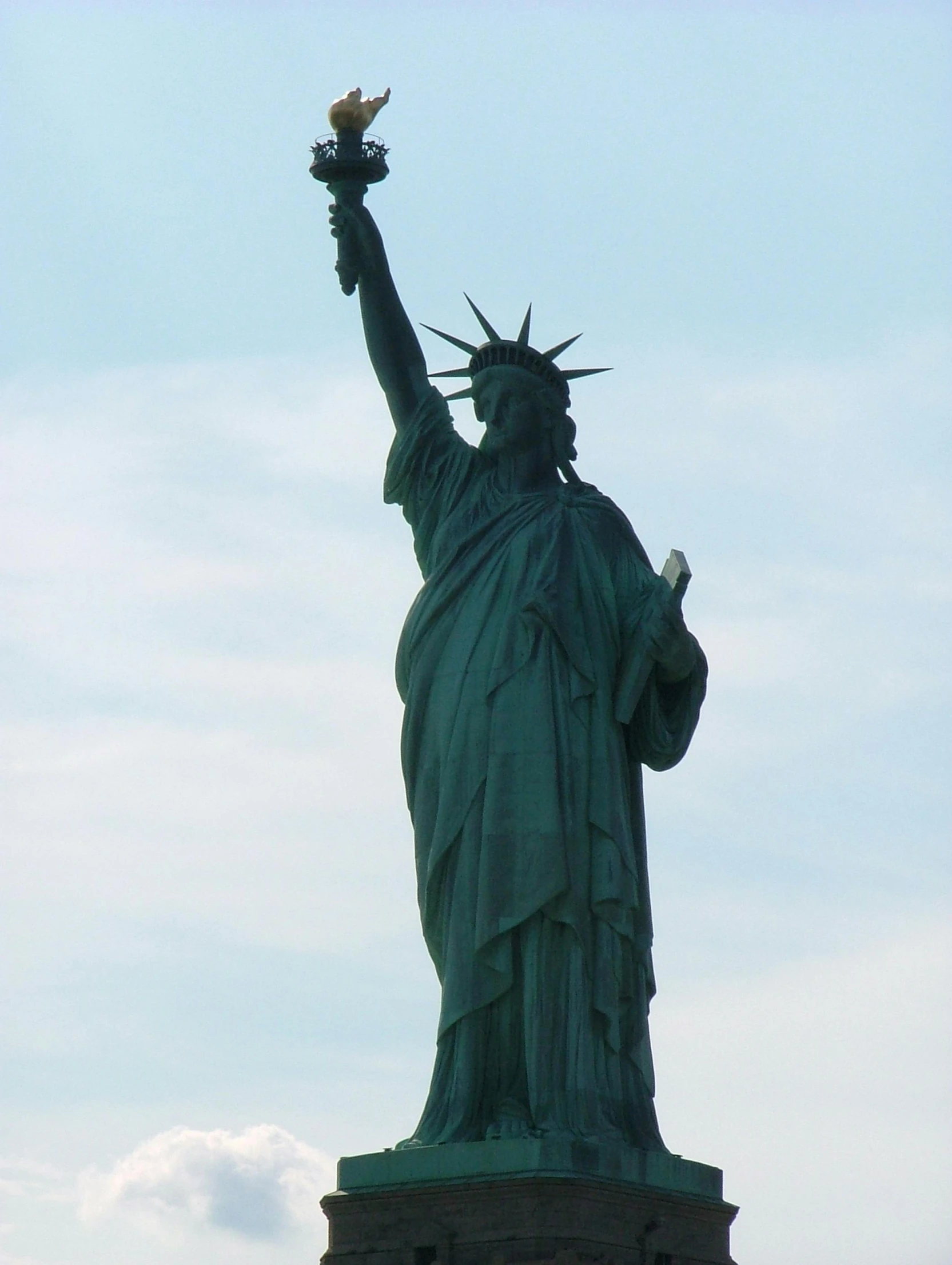 the statue of liberty stands tall in the sky, unsplash, shot on a 2 0 0 3 camera, view from the side”