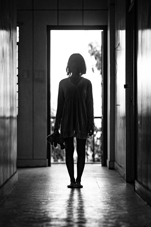 a black and white photo of a woman walking down a hallway, by Alexis Grimou, a portrait of a suicidal girl, standing near a window, comforting, silhoutte