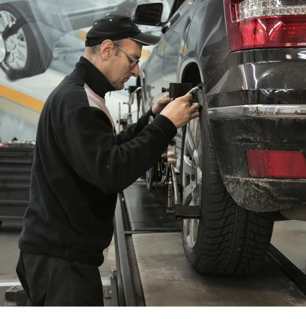 a man working on a car in a garage, a photo, arbeitsrat für kunst, detailed alloy wheels, thumbnail, tyre mark, highly technical