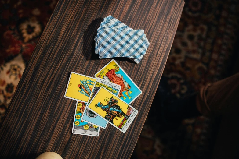 a wooden table topped with playing cards and a bow tie, a screenshot, unsplash, private press, tarot card the chariot, multicoloured, cowboy shot, sitting across the room