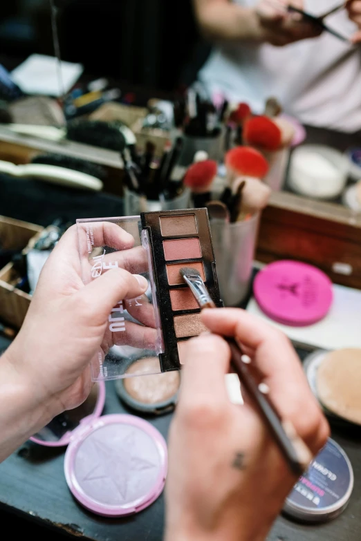 a woman is doing makeup in front of a mirror, a cartoon, trending on pexels, paintbrush and palettes, brown and pink color scheme, in a workshop, conor walton