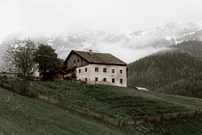 a house sitting on top of a lush green hillside, a black and white photo, inspired by Peter Zumthor, pexels contest winner, renaissance, gloomy earthy colors, alpine landscape with a cottage, a cozy, an abandoned old