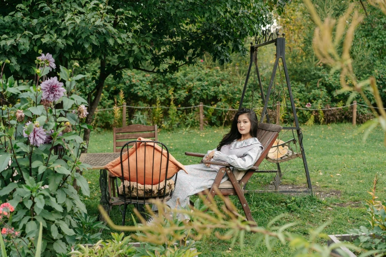 a woman sitting in a chair in a garden, cosy vibes, autumnal empress, teenager hangout spot, maria panfilova