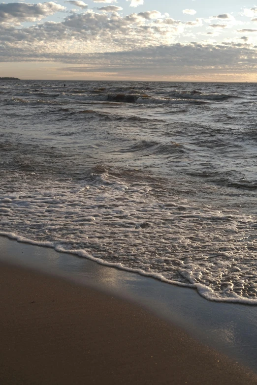 a man standing on top of a beach next to the ocean, wavy water, early evening, zoomed in, omaha beach