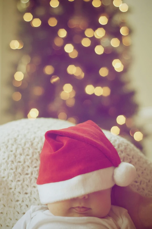 a baby wearing a santa hat in front of a christmas tree, a picture, by Julia Pishtar, bokeh ”, relaxing mood, thumbnail, etsy