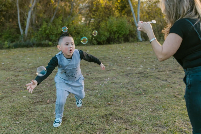 a woman and a child playing with soap bubbles, pexels contest winner, running towards camera, little boy, te pae, bubbles vfx
