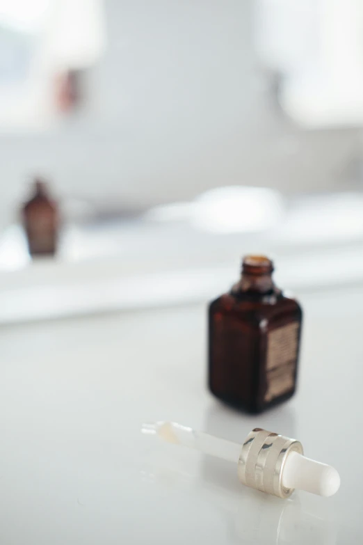 a bottle of liquid sitting on top of a counter, by Emily Shanks, unsplash, minimalism, in white room, vials, brown, bath