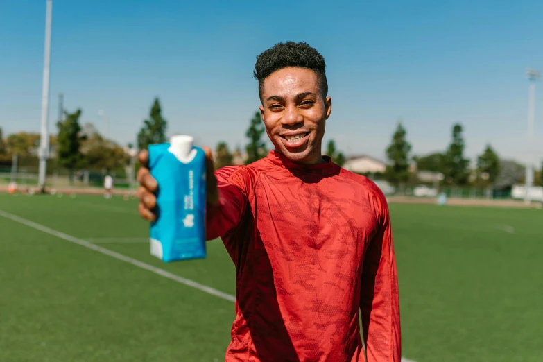 a young man holding a bottle of water on a soccer field, in style of tyler mitchell, silicone skin, highly upvoted, official product photo