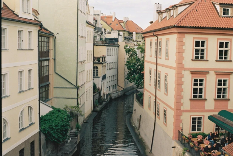 a river running through a city next to tall buildings, a photo, by Emma Andijewska, pexels contest winner, art nouveau, narrow and winding cozy streets, 2000s photo, mill, in the style wes anderson