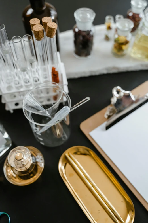 a clipboard sitting on top of a table next to a clipboard, a still life, process art, scientific glassware, gold, bartending, black