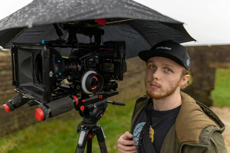 a man holding an umbrella over his head, a portrait, unsplash, arri alexa mini lf, portrait of sam hyde, looking to camera, red cinema camera