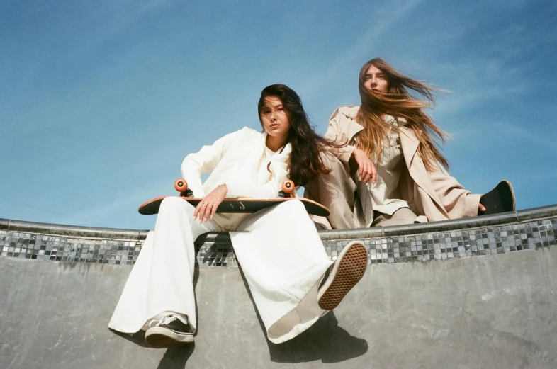 a couple of women sitting on top of a skateboard ramp, an album cover, by Emma Andijewska, unsplash, renaissance, wearing white suit, extremely long hair, photoshoot for skincare brand, uniform off - white sky