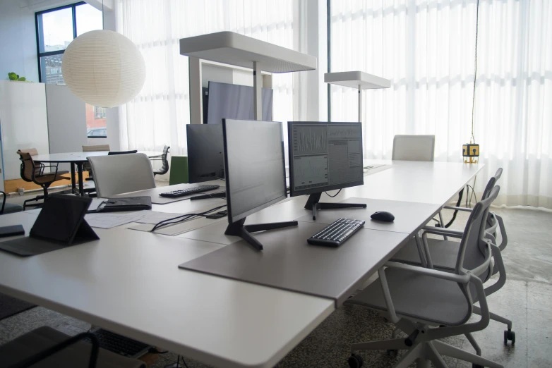 a couple of computers sitting on top of a white desk, inspired by Jakob Häne, light and space, engineering bay, a middle-shot from front, multiple desks, front lit