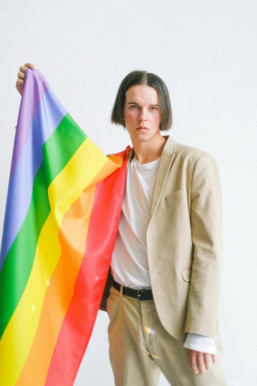 a man in a suit holding a rainbow flag, an album cover, by Jessie Alexandra Dick, unsplash, bauhaus, attractive androgynous humanoid, joe keery, 2019 trending photo, julian ope