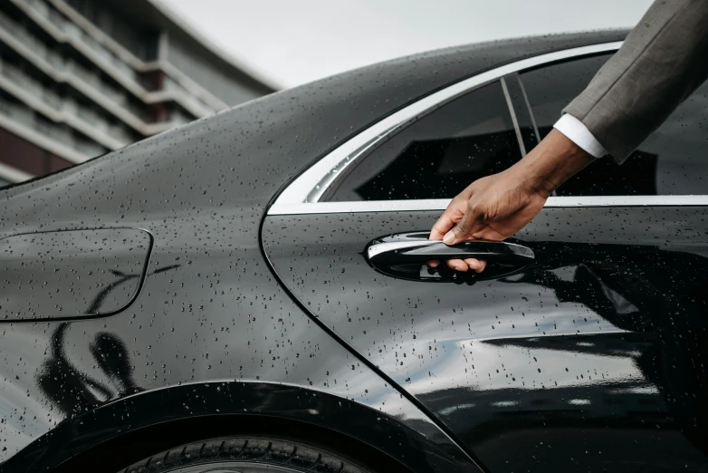 a man in a suit is opening the door of a car, pexels contest winner, 2 0 % pearlescent detailing, black car, up close, thumbnail