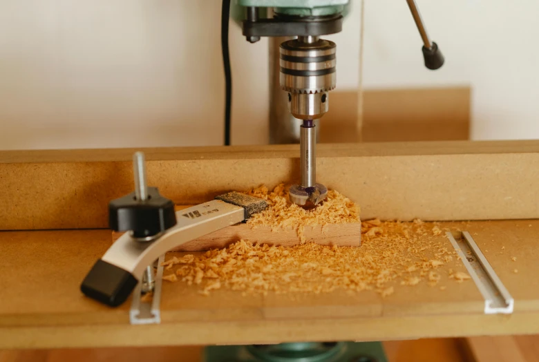 a drill sitting on top of a table next to a piece of wood, trending on pexels, mill, carefully crafted, spoon placed, mount