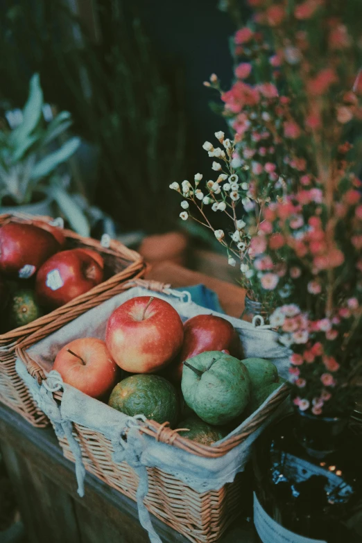 two baskets of fruit sitting on top of a table, flowers, grainy photograph, feature, apples