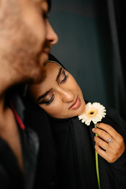 a man standing next to a woman holding a flower, trending on pexels, hurufiyya, detailed face of an arabic woman, tanned ameera al taweel, intimate, wearing black robe