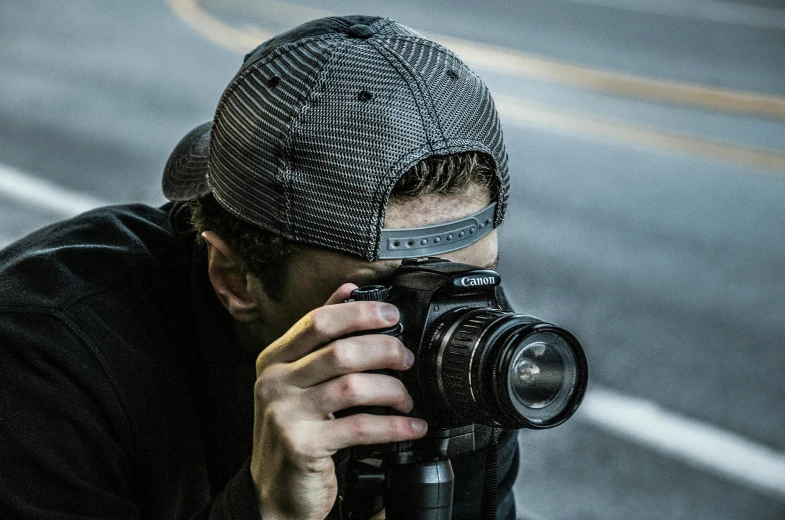 a man taking a picture with a camera, pexels contest winner, portrait of a vigilante, hacker, hat covering eyes, speed grapher