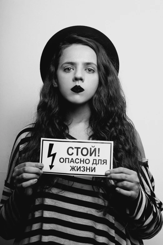 a black and white photo of a woman holding a sign, an album cover, by Alexander Litovchenko, tumblr, ((((lightning)))), teenager girl, scolding, dasha taran