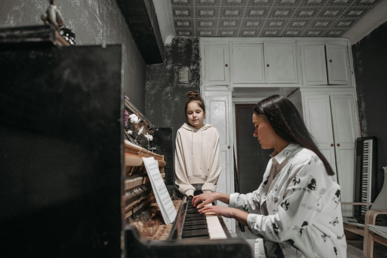 a woman standing next to a woman sitting at a piano, pexels contest winner, horror, children, profile image, thumbnail