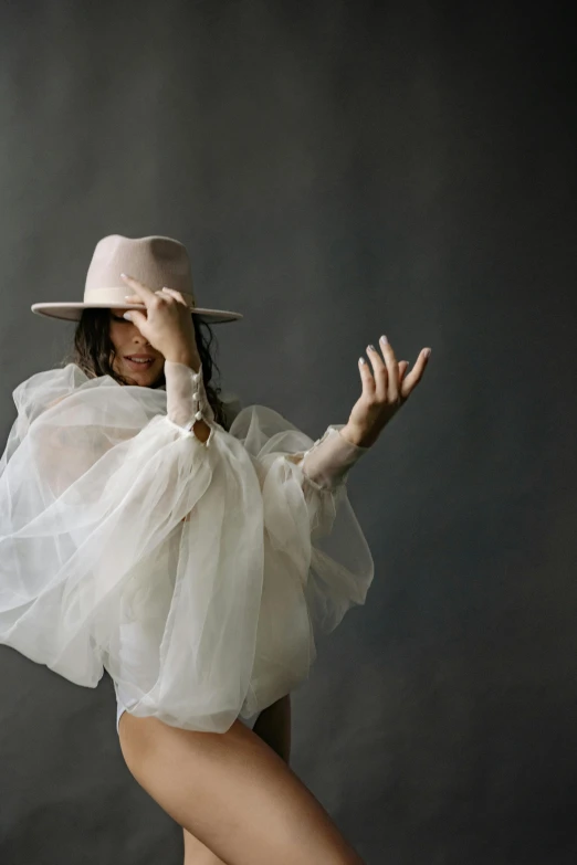 a woman in a white dress and a hat, an album cover, by Sara Saftleven, trending on pexels, gesture, beige mist, fashion designer, white and pink cloth