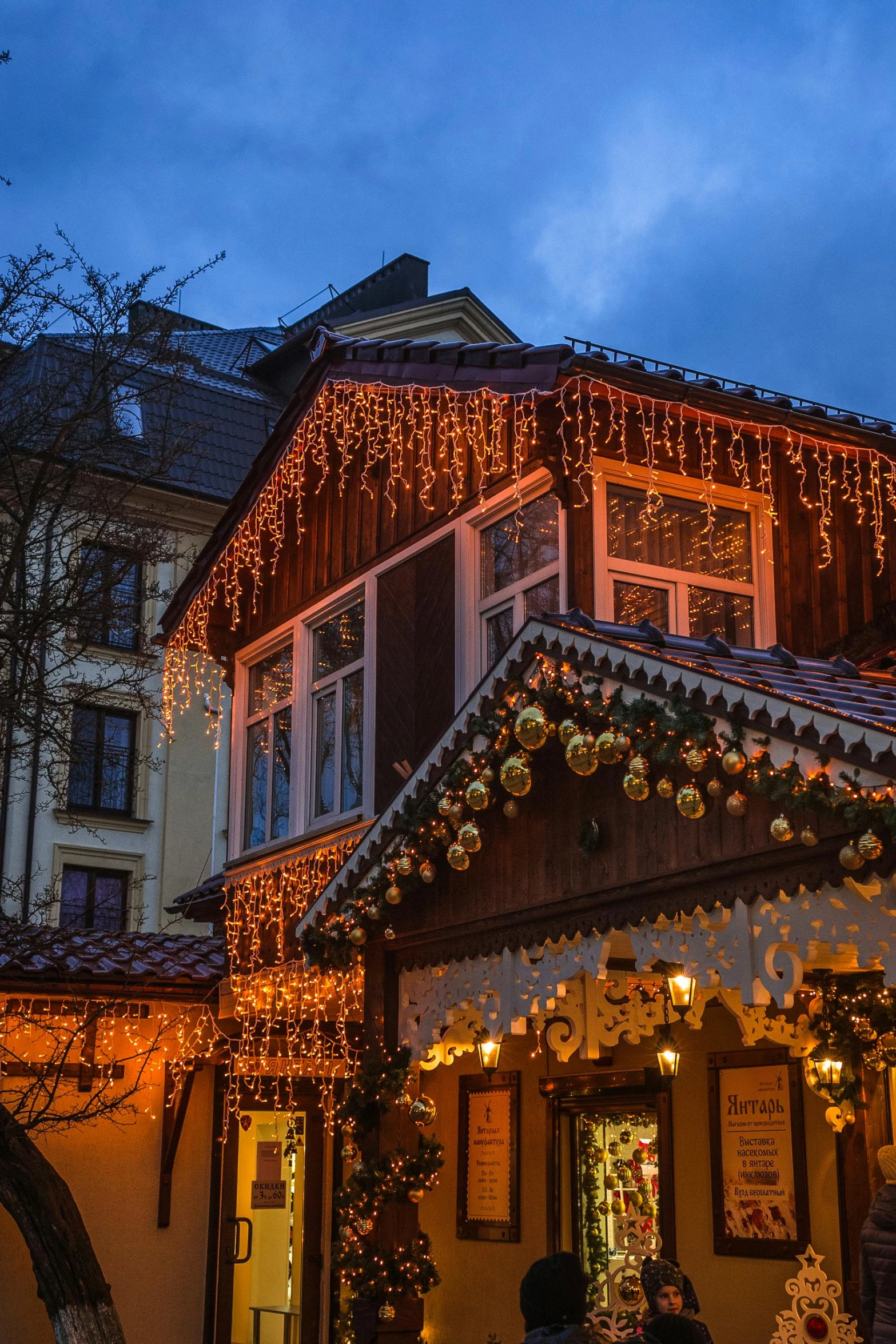 a couple of people that are standing in front of a building, decorations, warmly lit, swiss architecture, tiled roofs