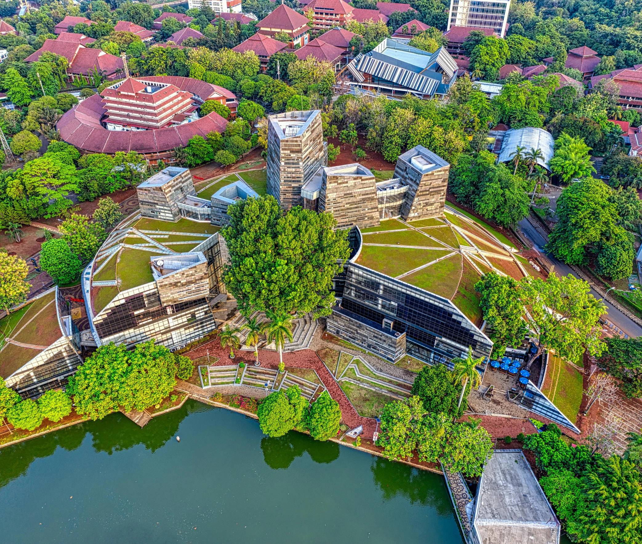 a bird's eye view of a city surrounded by trees, by Bernardino Mei, pexels contest winner, happening, brutalist aztec architecture, malaysian, university, build in a forest near of a lake