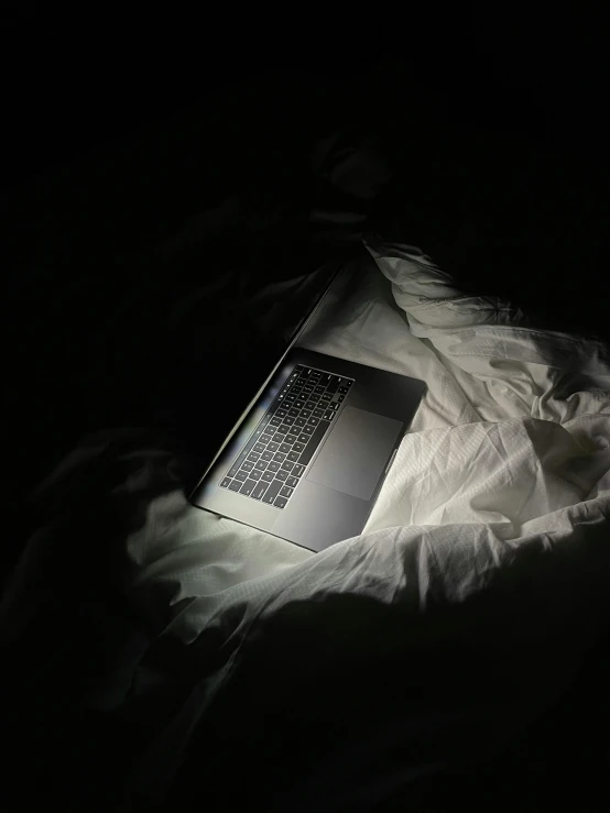 a laptop computer sitting on top of a bed, by Adam Rex, dark drapery, worn out, lit from above, lgbtq
