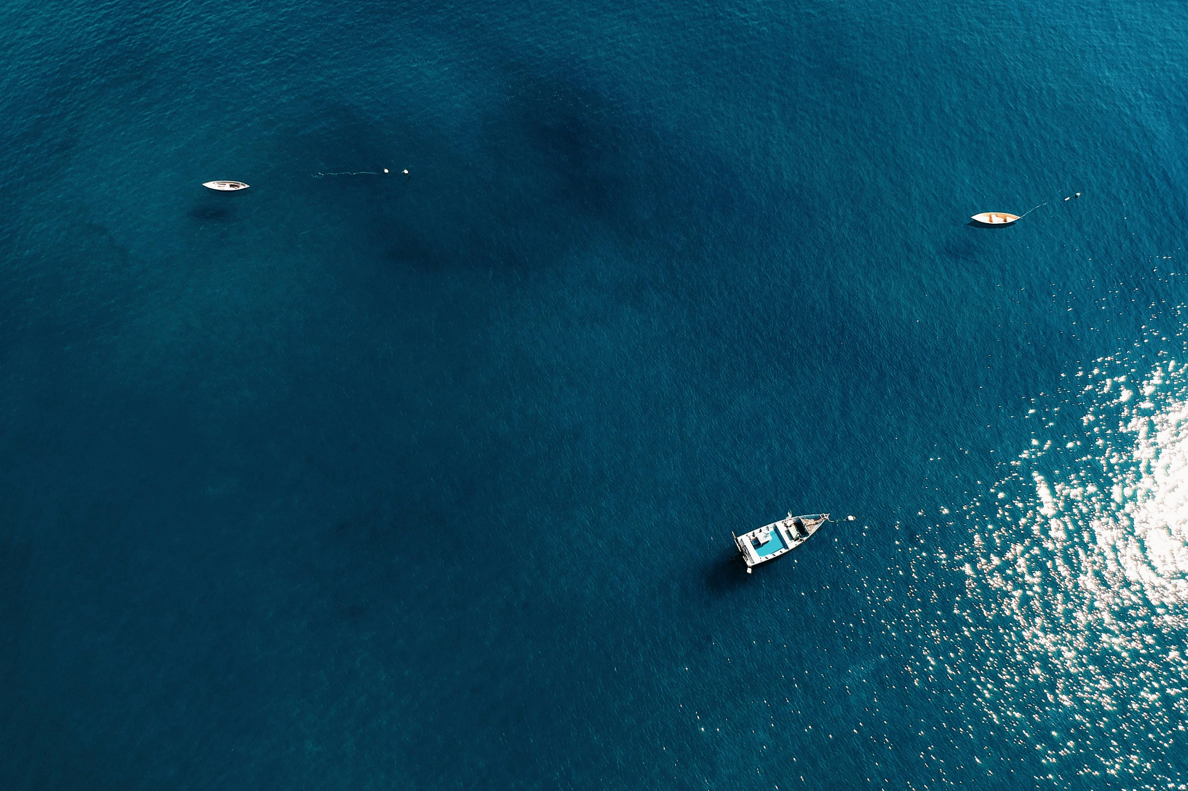 a group of boats floating on top of a body of water, pexels contest winner, minimalism, deep blue ocean color, thumbnail, helicopter view, gulf of naples