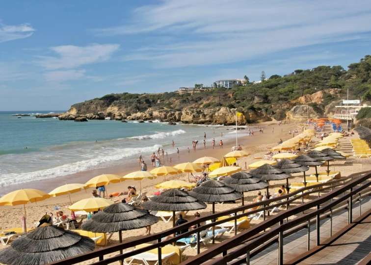 a beach filled with lots of umbrellas next to the ocean, rocha, white and yellow scheme, sparkling cove, camilo gc