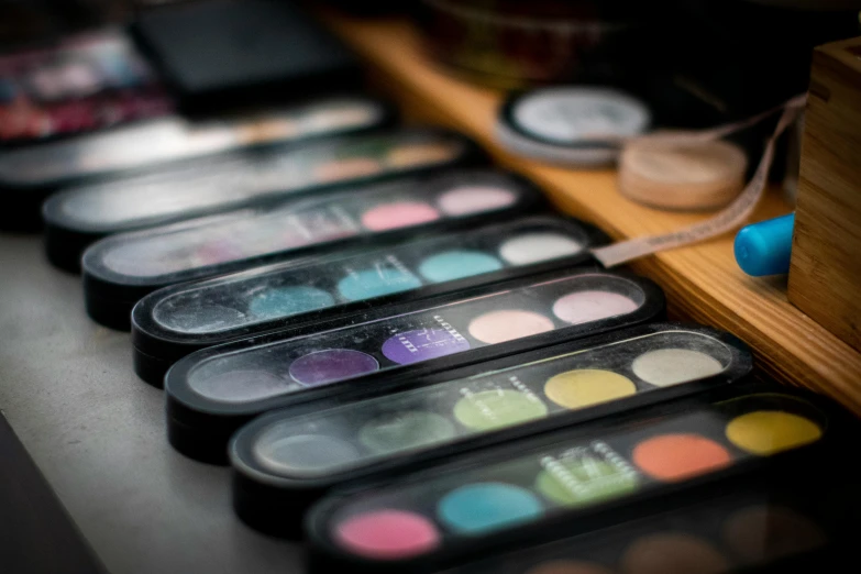 a table topped with lots of different colored eyeshadows, inspired by An Gyeon, trending on pexels, bauhaus, blurred, product showcase, vintage look, in a row