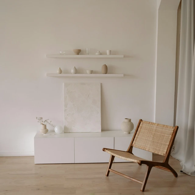 a wooden chair sitting on top of a hard wood floor, a minimalist painting, by Adam Pijnacker, pexels contest winner, minimalism, shelves, organic ceramic white, wicker chair, interior of a small