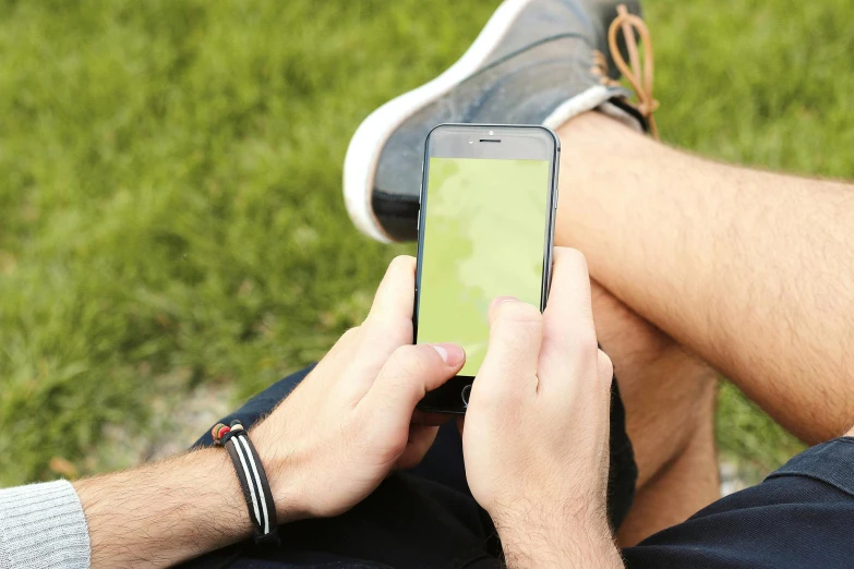 a close up of a person holding a cell phone, a picture, sitting on green grass, 15081959 21121991 01012000 4k, gradient green black, male teenager