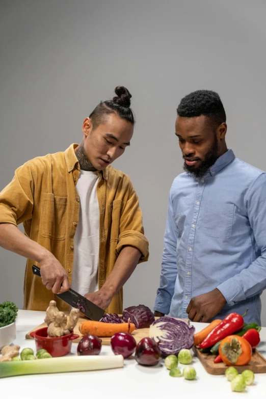 two men are cutting vegetables on a table, by Sam Charles, pexels contest winner, model posing, varying ethnicities, kda and sam yang, looking to the side off camera