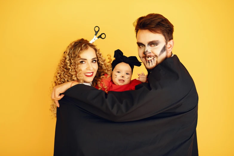 a man and woman in halloween costumes holding a baby, pexels, antipodeans, portrait image, black and yellow, scissor people, multi-part