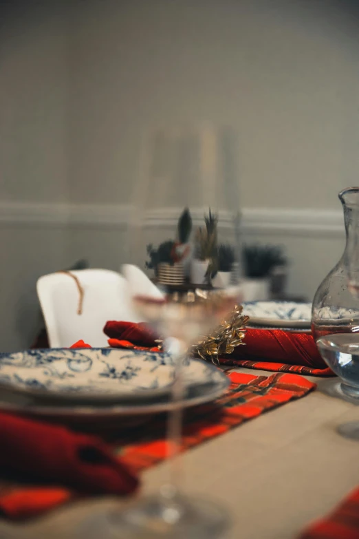 a close up of a table with plates and glasses, profile image, holiday vibe, blue colors with red accents, 4l