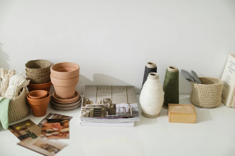 a white table topped with pots and magazines, a still life, unsplash, process art, sustainable materials, weaving, terracotta, advertising photograph