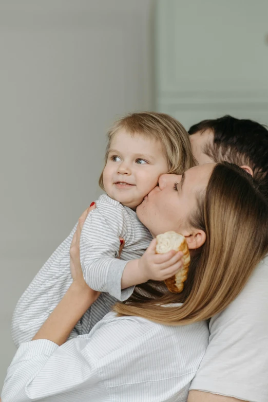 a woman holding a small child in her arms, pexels contest winner, couple kissing, plain background, snacks, profile image