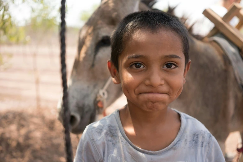 a young boy standing in front of a donkey, pexels contest winner, indian girl with brown skin, thumbnail, multiple stories, close up face