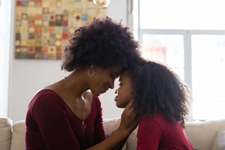 a woman and a little girl sitting on a couch, pexels, natural hair, touching heads, garnet, looking at each other mindlessly