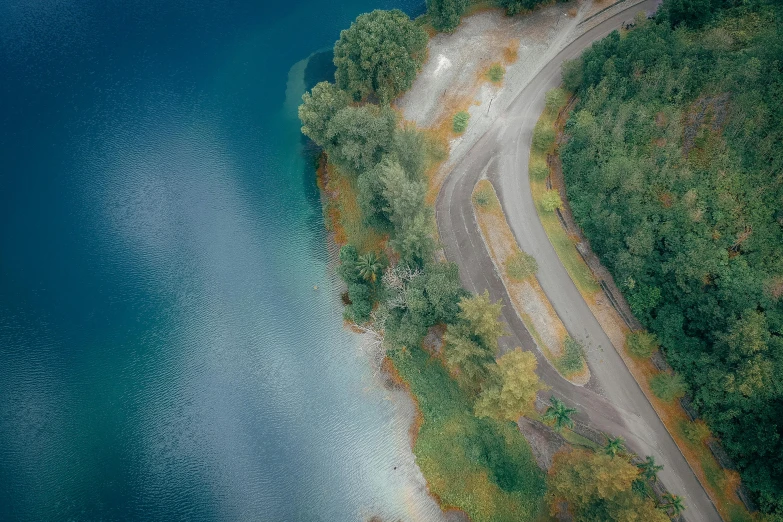 an aerial view of a road next to a body of water, pexels contest winner, realism, paul barson, shore of the lake, half turned around, switzerland